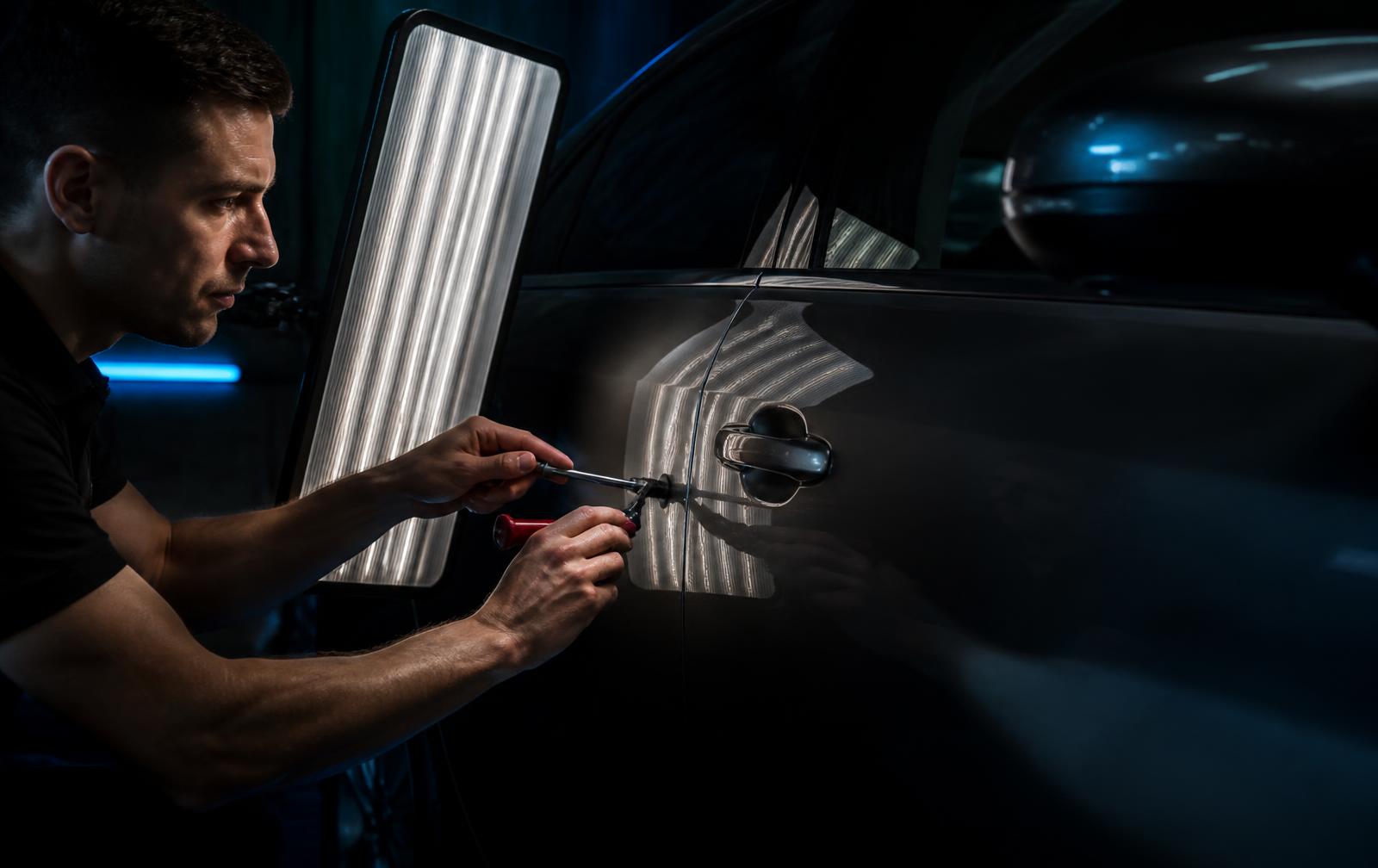 Pure PDR technician performing paintless dent repair using a panel reading light board